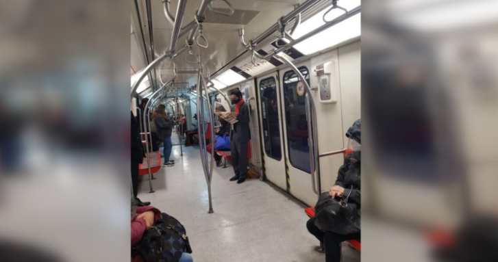 Fotografían a ministro Briones en Metro camino al trabajo: de pie, leyendo el diario y con escoltas